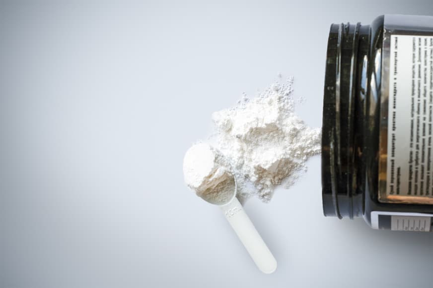 Potje met creatine poeder en schepje met creatine eruit